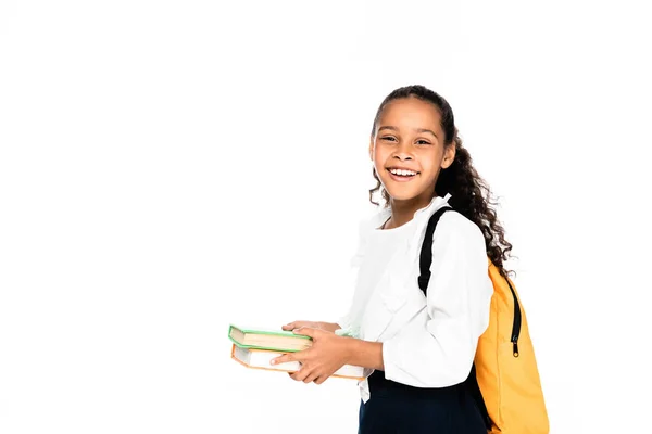 Glücklich afroamerikanische Schulmädchen lächelt in die Kamera, während sie Bücher isoliert auf weiß hält — Stockfoto