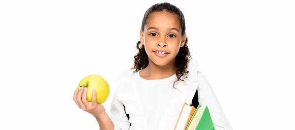Panoramic shot of cute african american schoolgirl holding books and apple isolated on white — Stock Photo