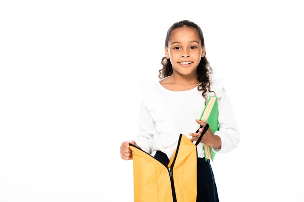 Fröhliche afrikanisch-amerikanische Schülerin mit Rucksack und Buch isoliert auf weiß — Stockfoto