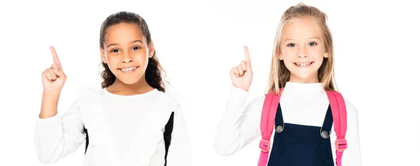 Plano panorámico de dos lindas colegialas multiculturales mostrando gestos de idea aislados en blanco - foto de stock