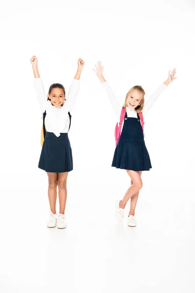 Full length view of two happy multicultural schoolgirls showing yes gestures on white background — Stock Photo