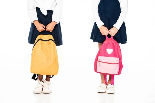 Cropped view of two multicultural schoolgirls holding backpacks on white background — Stock Photo