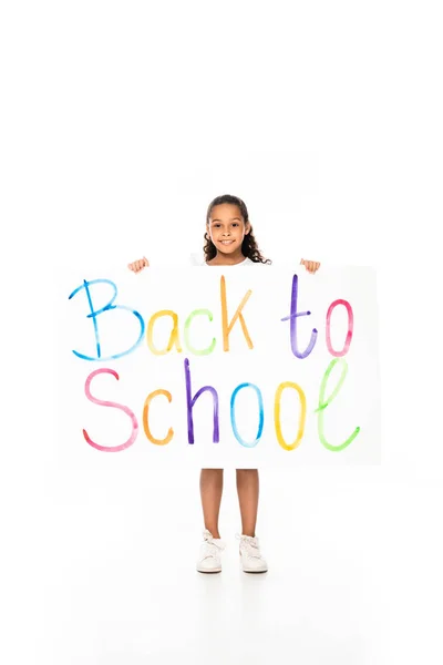 Cheerful african american schoolgirl holding placard with back to school inscription on white background — Stock Photo
