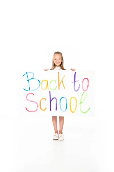 Jolie écolière tenant la pancarte avec dos à l'inscription de l'école sur fond blanc — Photo de stock