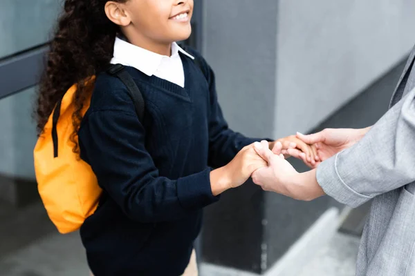 Cropped view of woman holding hands of adopted african american daughter — Stock Photo