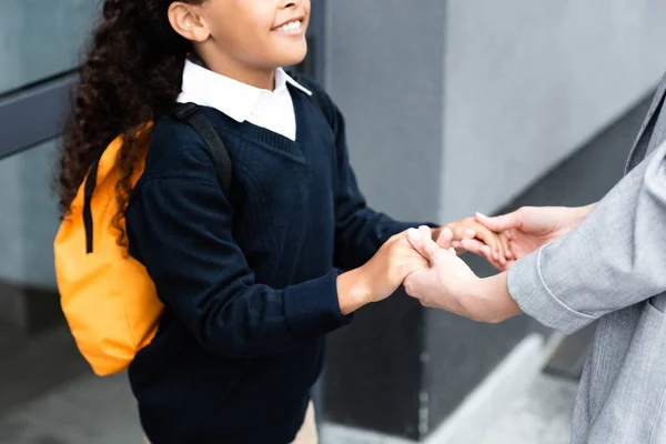 Abgeschnittene Ansicht einer Frau, die die Hände ihrer adoptierten afrikanisch-amerikanischen Tochter hält — Stockfoto