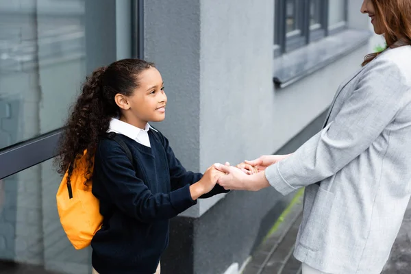 Abgeschnittene Ansicht einer Frau, die glückliche, adoptierte afrikanisch-amerikanische Tochter hält, die zur Schule geht — Stockfoto