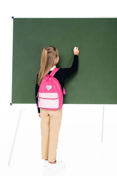 Back view of schoolgirl with pink backpack writing on green chalkboard on white background — Stock Photo