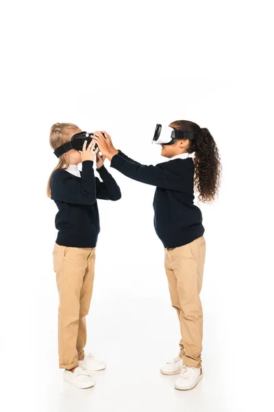 Vista completa de dos amigos multiculturales usando auriculares de realidad virtual sobre fondo blanco - foto de stock