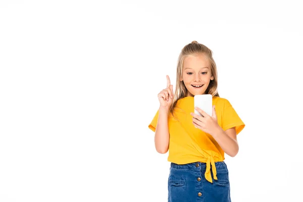 Niño alegre mostrando gesto de idea durante el uso de teléfono inteligente aislado en blanco - foto de stock