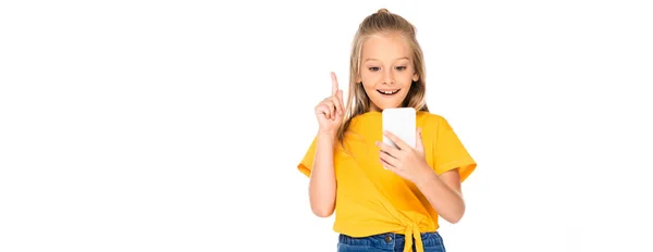 Plan panoramique de l'enfant joyeux montrant geste idée tout en utilisant smartphone isolé sur blanc — Photo de stock