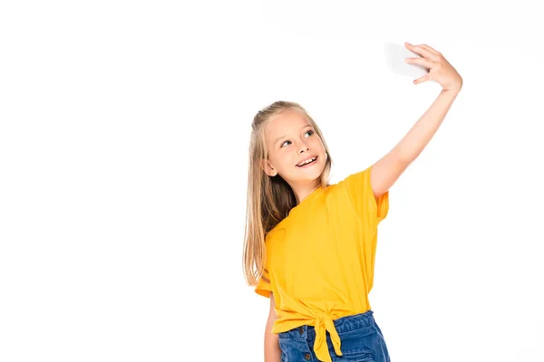 Criança feliz sorrindo enquanto toma selfie com smartphone isolado no branco — Fotografia de Stock