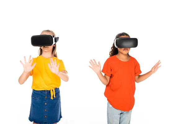 Dos amigos multiculturales lindos usando auriculares de realidad virtual aislados en blanco - foto de stock