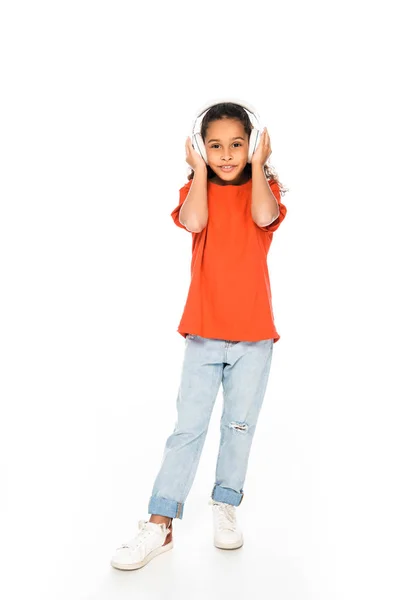 Full length view of cute african american child listening music in headphones on white background — Stock Photo