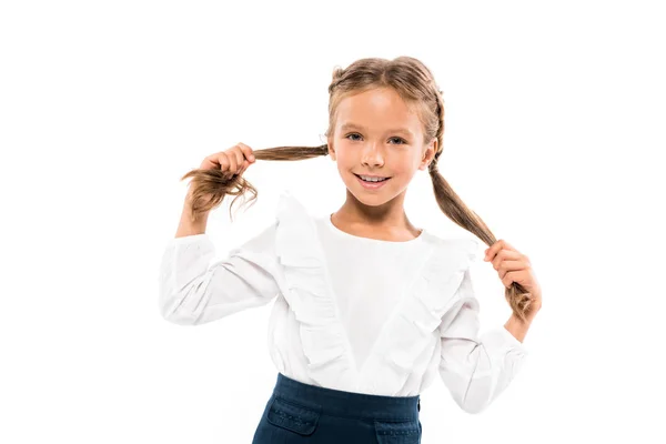 Весела дитина торкається волосся, дивлячись на камеру ізольовано на білому — стокове фото