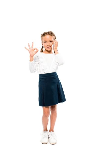 Glückliches Kind zeigt ok Zeichen während des Gesprächs auf dem Smartphone isoliert auf weiß — Stockfoto