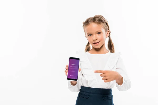 KYIV, UCRAINA - 17 LUGLIO 2019: bambino felice che punta il dito contro lo smartphone con l'app instagram isolata sul bianco — Foto stock