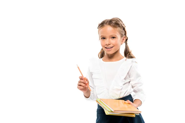 Criança alegre que prende livros e lápis isolados no branco — Fotografia de Stock