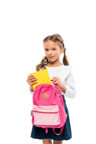 Glückliches Kind legt Buch in rosa Rucksack isoliert auf weiß — Stockfoto