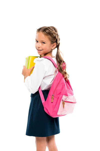 Glückliches Kind, das Bücher in der Hand hält und mit rosa Rucksack auf weißem Hintergrund steht — Stockfoto