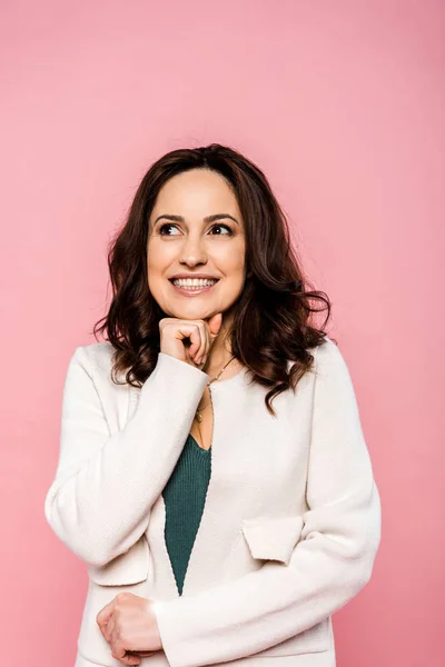 Sonriente y atractiva mujer tocando la cara aislada en rosa - foto de stock