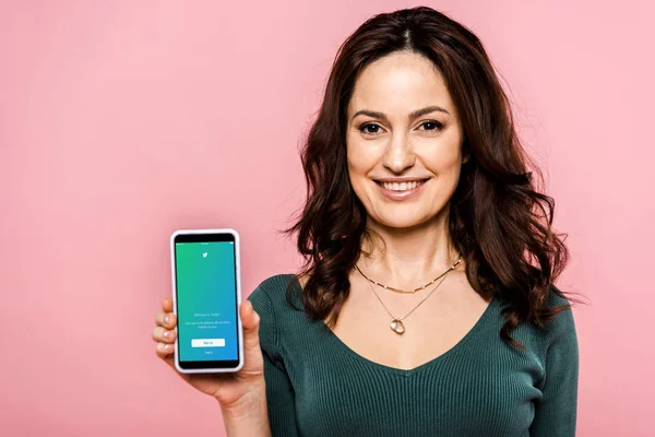 KYIV, UKRAINE - JULY 17, 2019: happy woman holding smartphone with twitter app on screen isolated on pink — Stock Photo