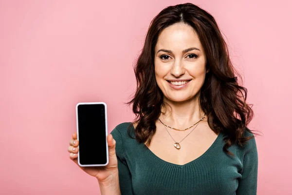 Mulher feliz segurando smartphone com tela em branco isolado em rosa — Fotografia de Stock