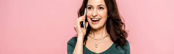 Foto panorámica de la mujer feliz hablando en el teléfono inteligente aislado en rosa - foto de stock