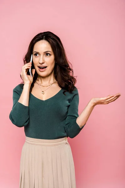 Mujer emocional hablando en el teléfono inteligente y el gesto aislado en rosa - foto de stock