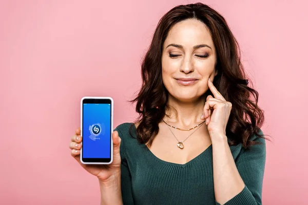 Kyiv, ukraine - 17. Juli 2019: glückliche Frau hält Smartphone mit Shazam-App auf dem Bildschirm isoliert auf rosa — Stockfoto