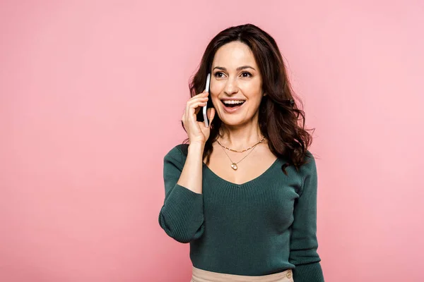 Mujer feliz hablando en el teléfono inteligente y sonriendo aislado en rosa - foto de stock