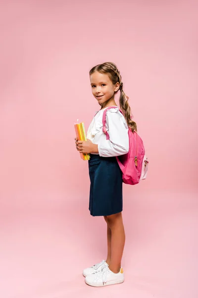 Glückliches Kind, das Bücher hält und isoliert auf rosa steht — Stockfoto