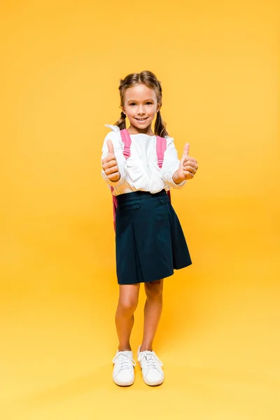 Happy kid standing and showing thumbs up on orange — Stock Photo