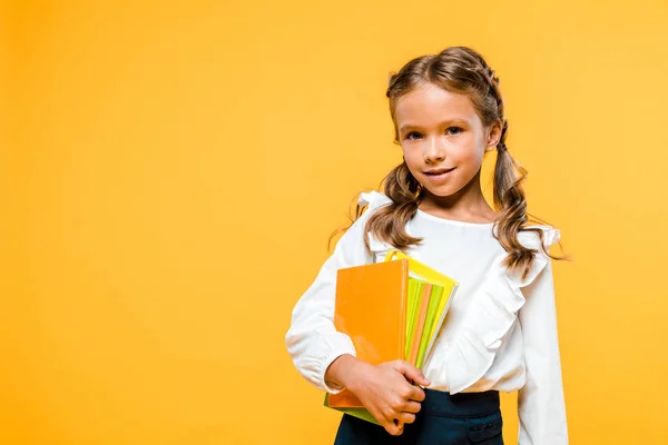 Lächelndes und niedliches Kind, das Bücher isoliert auf orange hält — Stockfoto