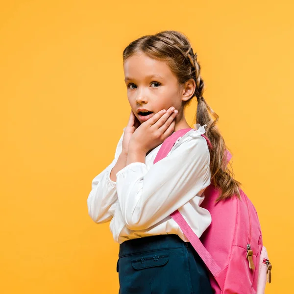 Schockiertes Schulkind berührt Gesicht und blickt in Kamera isoliert auf orange — Stockfoto