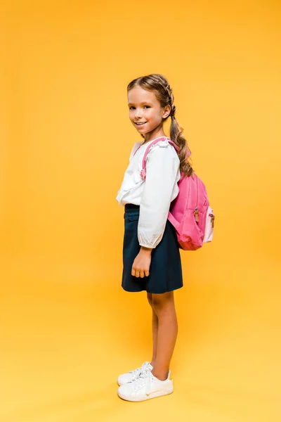 Glückliches Schulkind, das in die Kamera schaut, während es auf Orange steht — Stockfoto