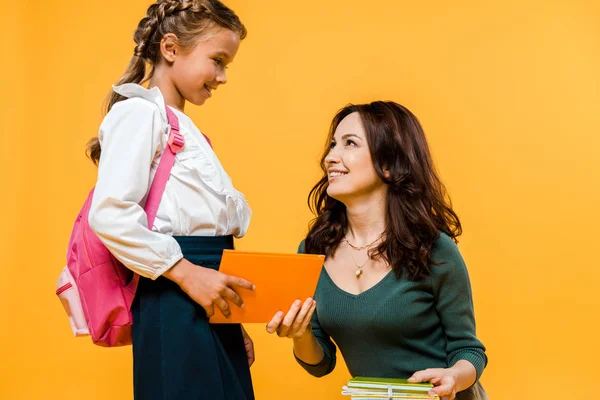 Mãe atraente dando livro para colegial feliz isolado em laranja — Fotografia de Stock