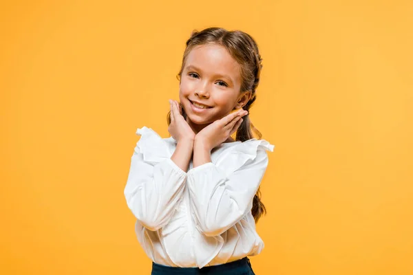 Cheerful schoolgirl smiling and looking at camera isolated on orange — Stock Photo