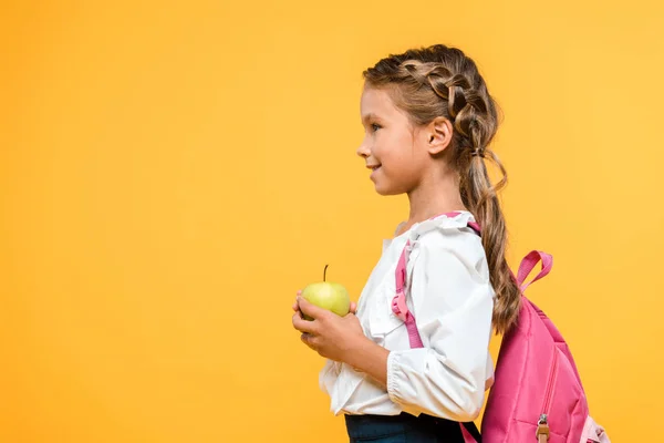 Seitenansicht eines glücklichen Schulkindes, das Apfel isoliert auf Orange hält — Stockfoto