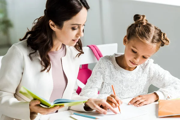 Schöne Mutter sieht Tochter Zeichnung zu Hause — Stockfoto