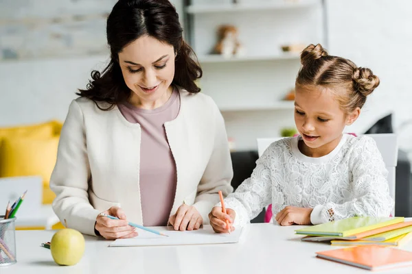 Cheerful mother and daughter drawing on paper — Stock Photo