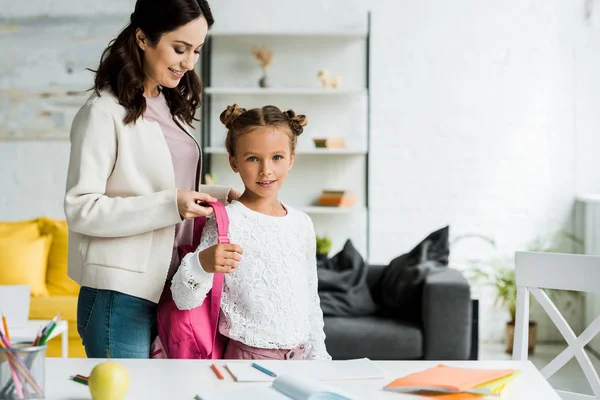 Mère heureuse décoller sac à dos de fille mignonne — Photo de stock