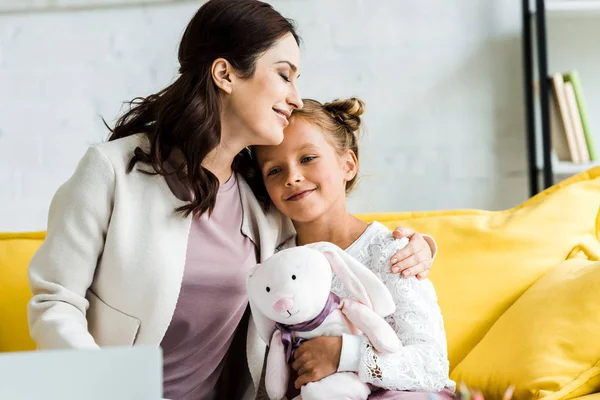 Happy woman smiling while hugging daughter with soft toy — Stock Photo