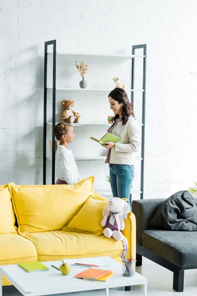 Enfoque selectivo de la madre y la hija de pie en la sala de estar - foto de stock