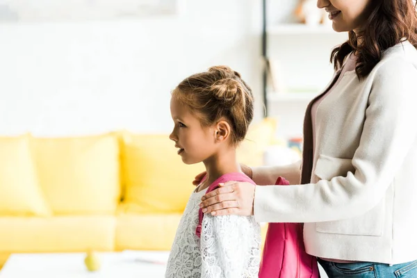 Vue recadrée de la mère touchant les épaules de la fille dans le sac à dos — Photo de stock