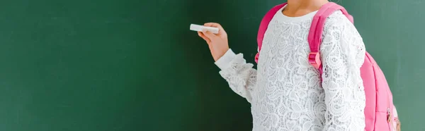 Panoramic shot of kid with backpack holding chalk — Stock Photo