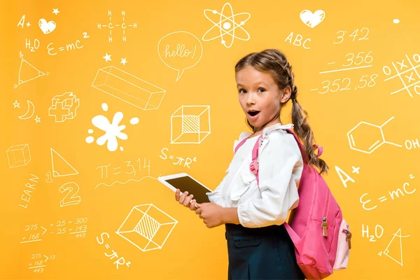 Surprised schoolkid holding digital tablet with blank screen near mathematical formulas on orange — Stock Photo