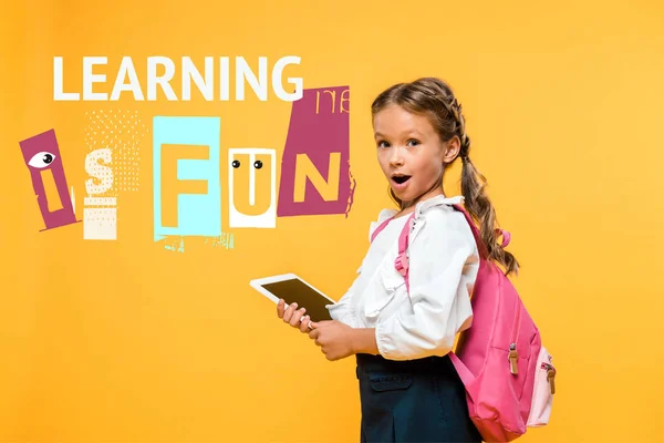 Surprised schoolkid holding digital tablet with blank screen near learning in fun lettering on orange — Stock Photo