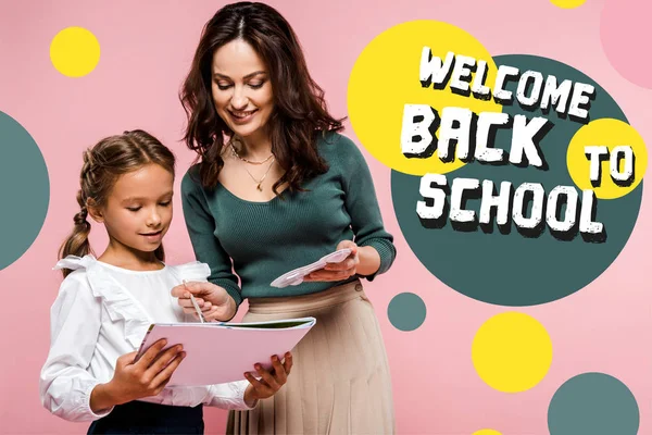 Glückliche Mutter steht neben süßer Tochter und begrüßt zurück in der Schule Schriftzug beim Malen auf rosa — Stockfoto