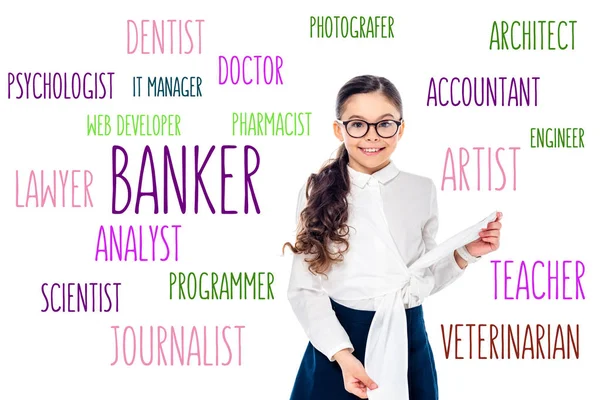 Smiling schoolgirl in formal wear and glasses looking at camera near lettering with professions on white — Stock Photo